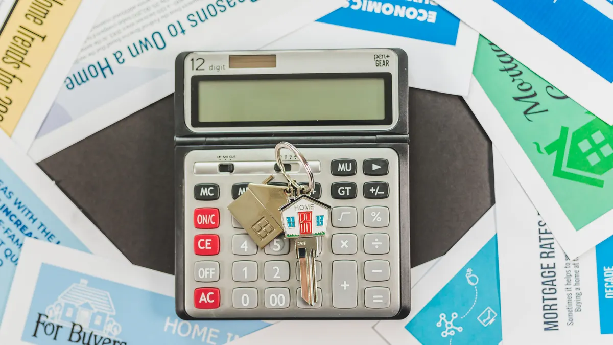 Calculator on mortgage papers with house keys