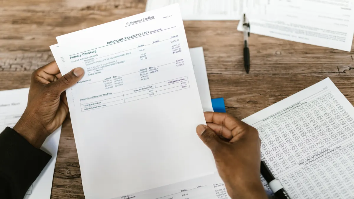 Hands comparing printed documents at a table