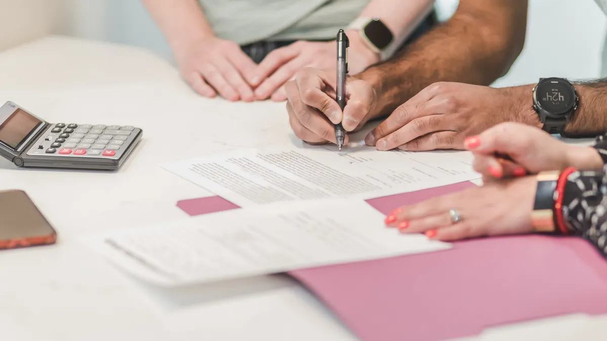 People reviewing forms with a calculator on the table