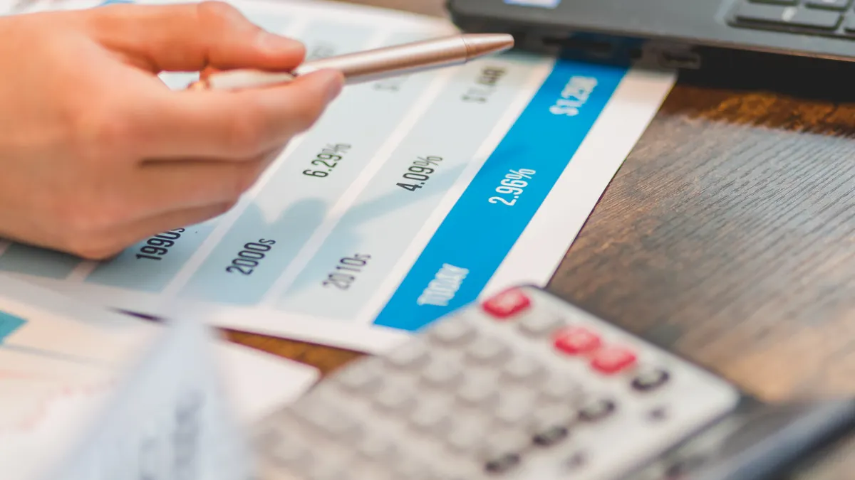 hand reviewing a payment schedule chart near a laptop and calculator