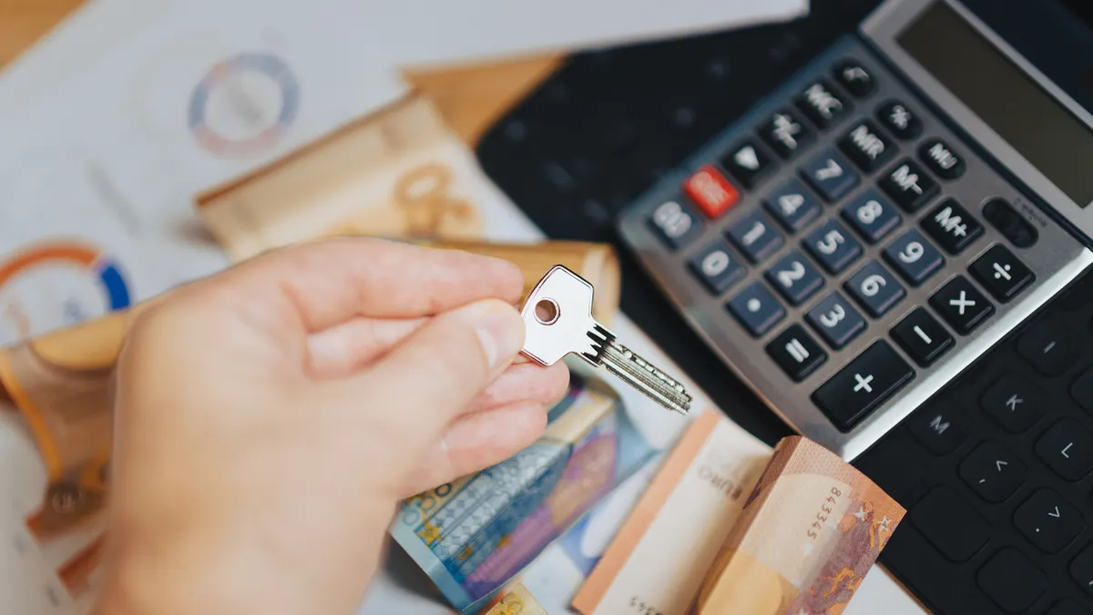 How to compare variable payment loan features and payment caps Hand holding a key near a calculator and banknotes