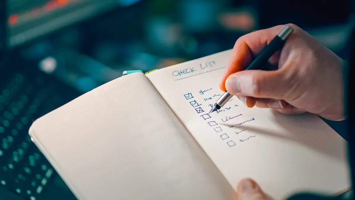 Hand checking off items in a notebook checklist