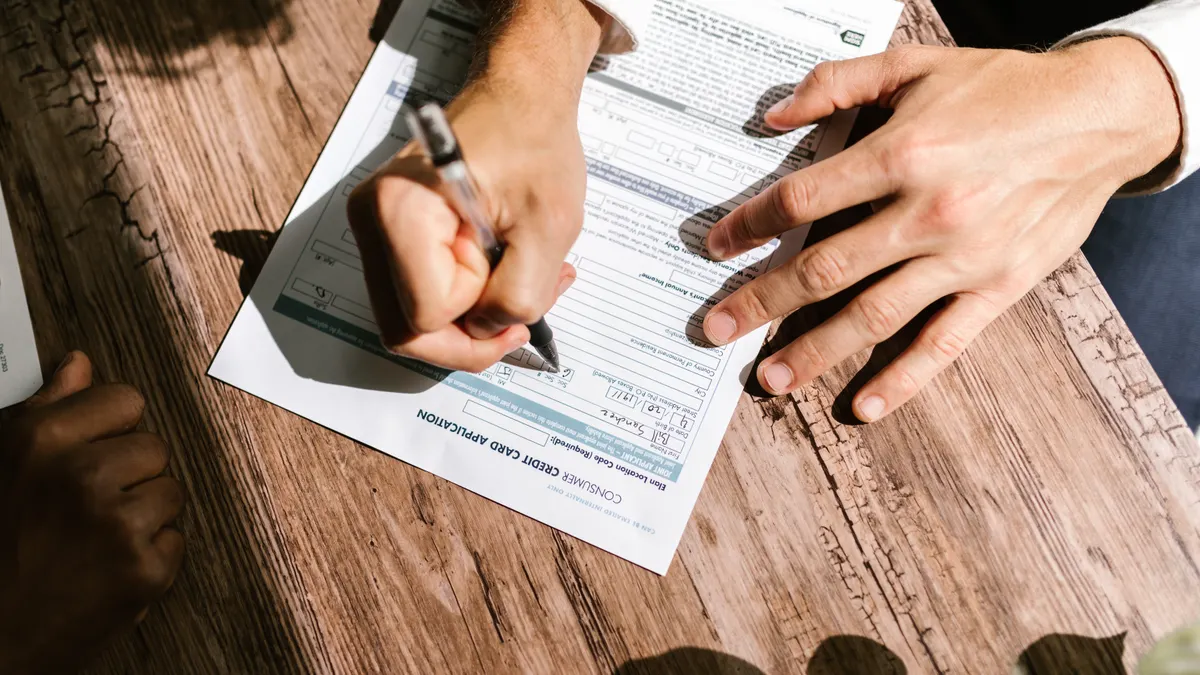 Person filling out a financial form on a clipboard